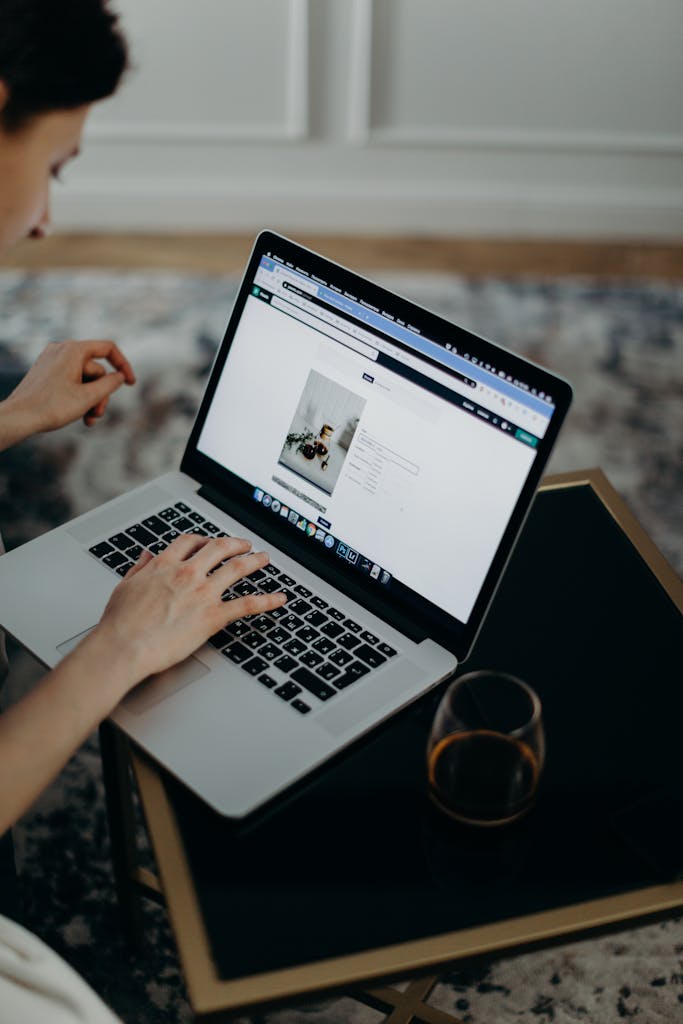 Close-up of a person working remotely on a laptop indoors. Ideal for remote work or technology themes.